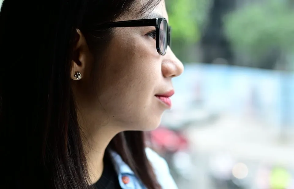 A professional standing by a window in soft daylight, looking out