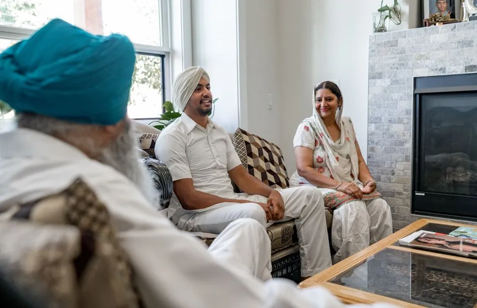 Three adults sitting together and talking in a sunlit living room
